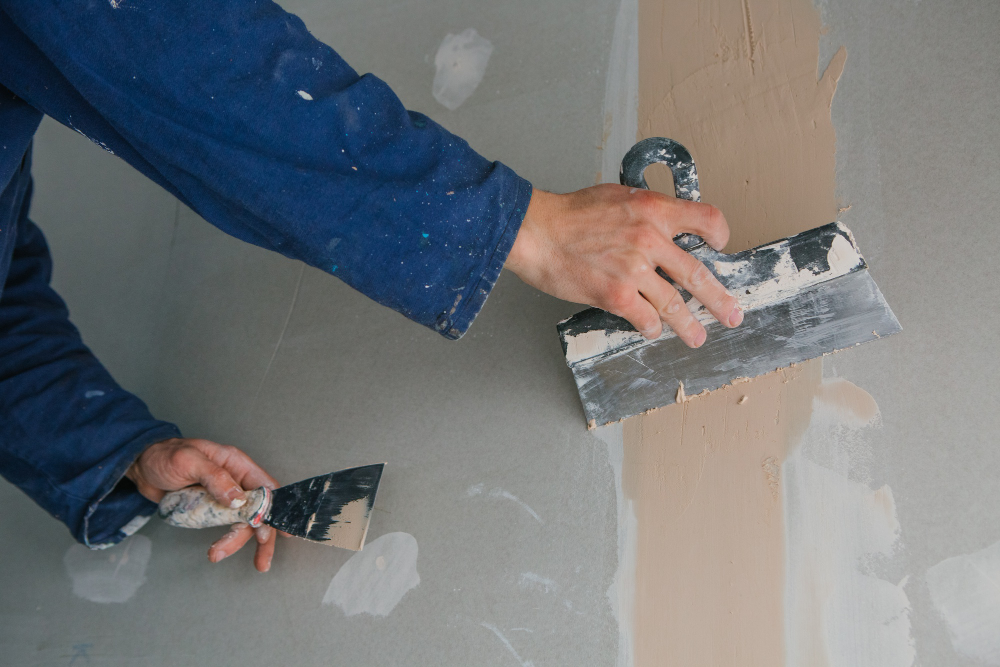 plasterer-man-works-plastering-two-trowels-plasterboard-blue-uniform